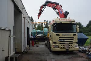 Lutter Spedition NRW - Betriebsumzüge - Maschinentransport - Logistik - Lkw mit Kran hebt eine Maschine auf die Ladeflaeche